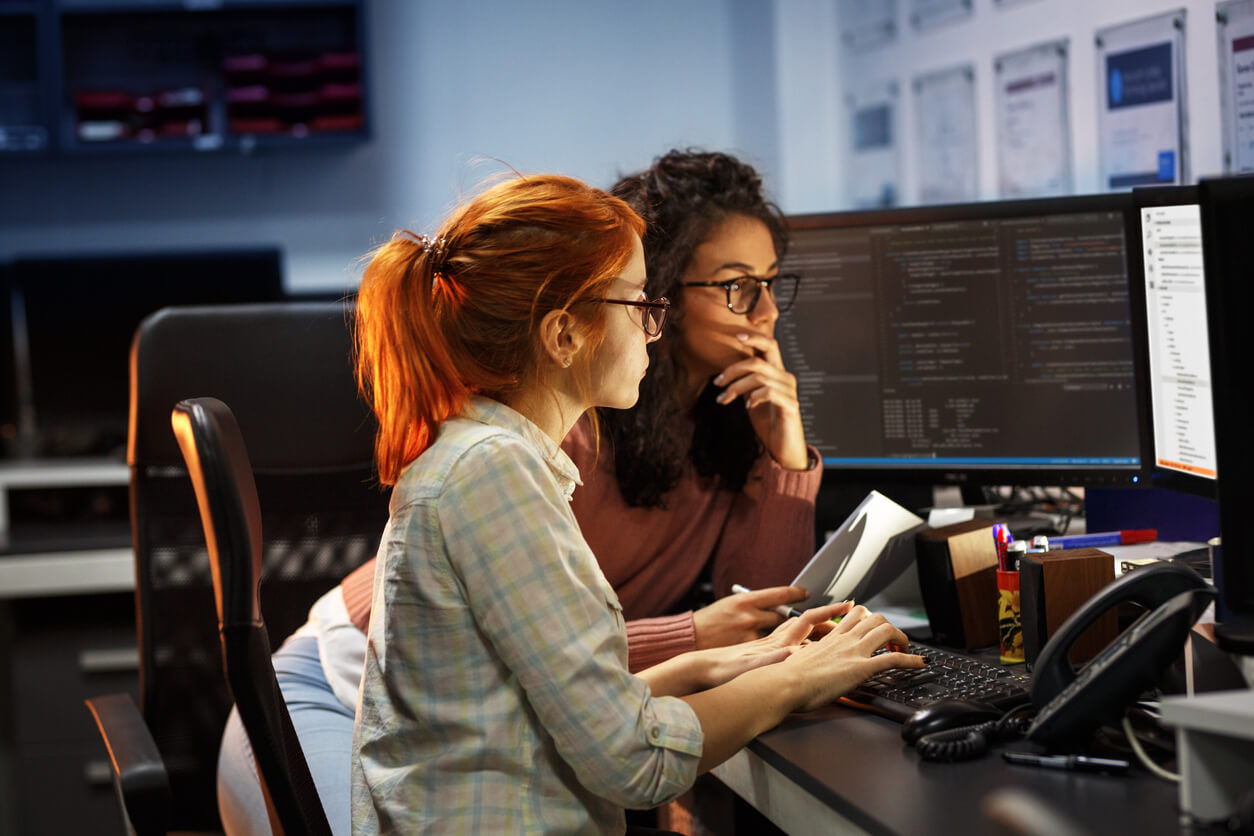 Duas programadoras trabalham juntas em projeto.