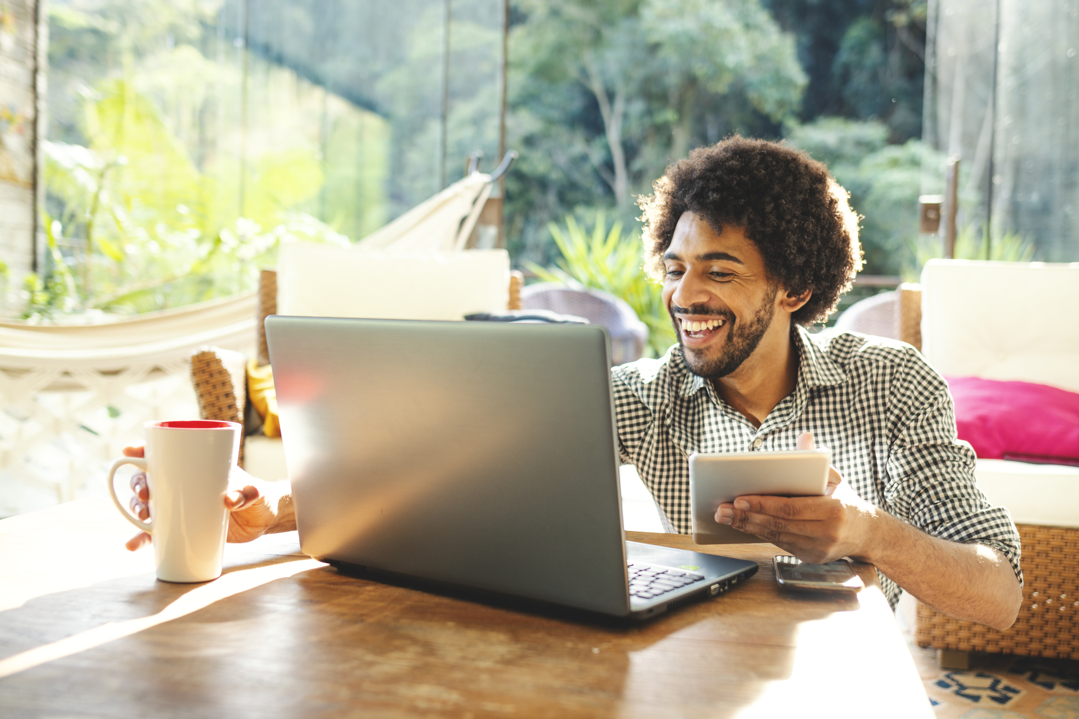 Desenvolvedor sorridente trabalha em casa com café