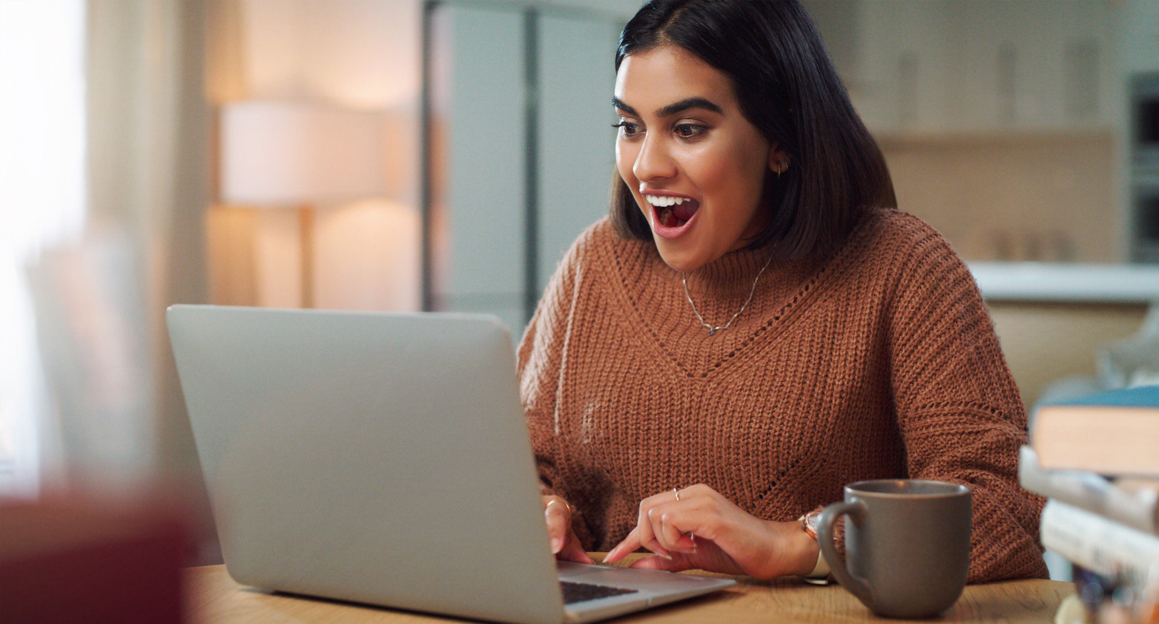 Empreendedora com expressão alegre acessando o notebook.