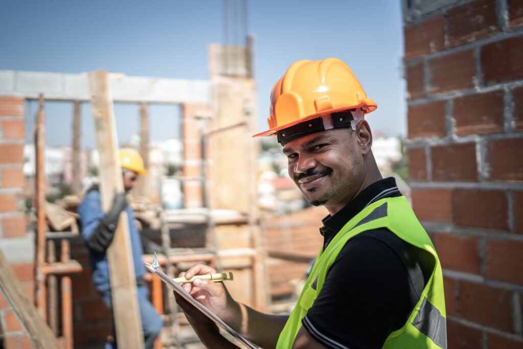 Retrato de um pedreiro segurando uma prancheta trabalhando em um canteiro de obras