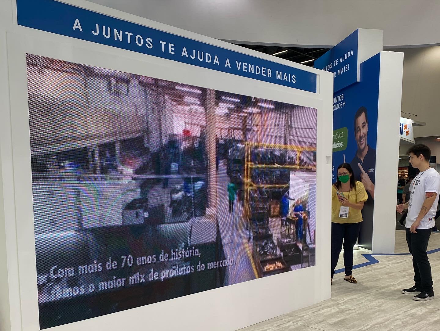 Painel luminoso da Juntos Somos Mais na FEICON com os dizeres “A Juntos te ajuda a vender mais”.