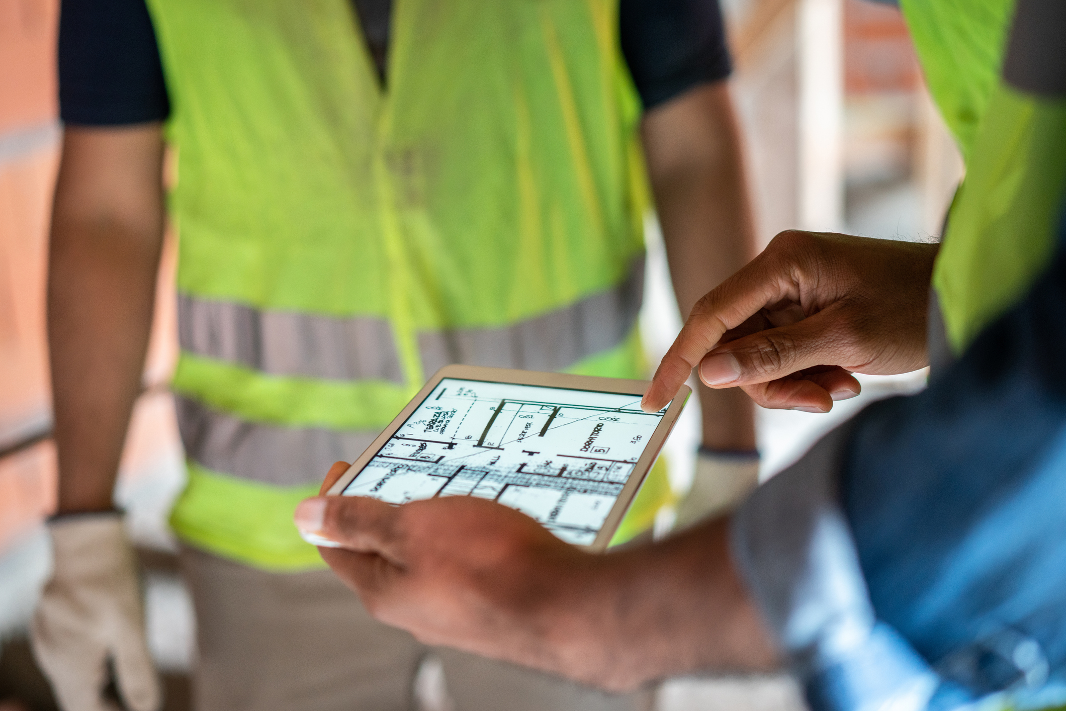 Engenheiro em canteiro de obras revisando plantas em tablet digital