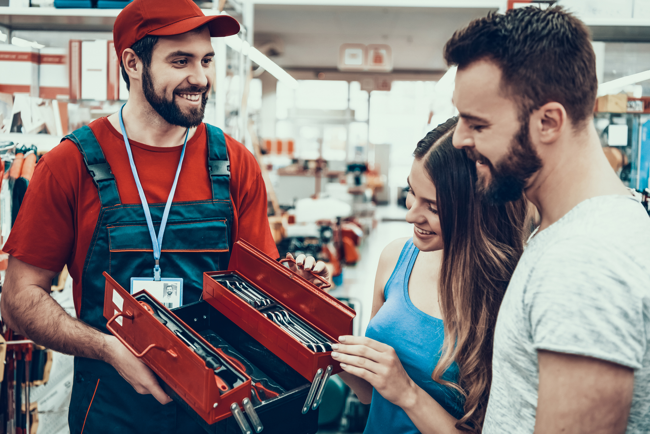 Vendedor mostrando uma caixa de ferramentas nova para clientes que estão sorridentes