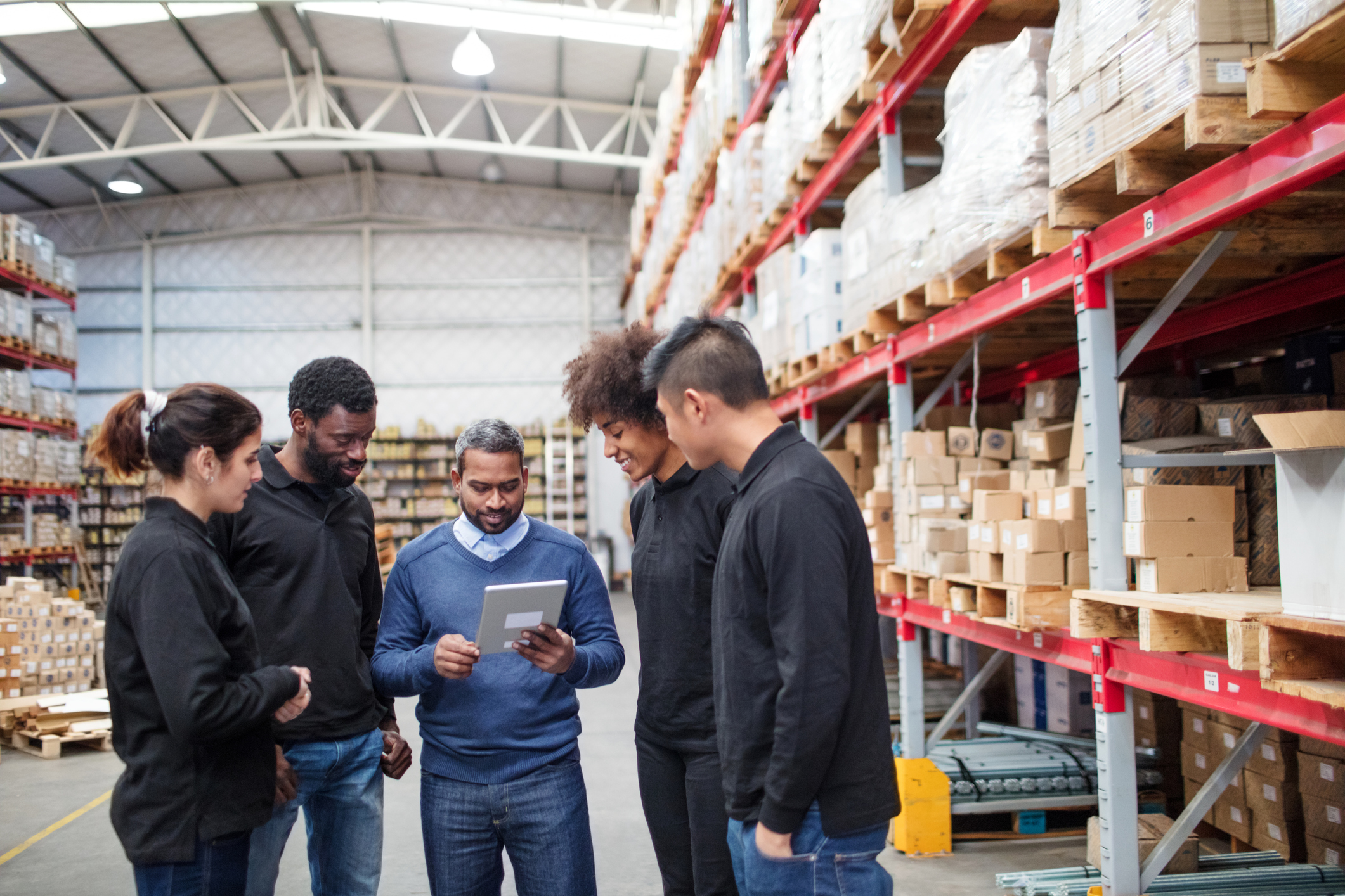 Gerente de loja de material de construção trabalhando a comunicação interna enquanto conversa com a equipe no estoque