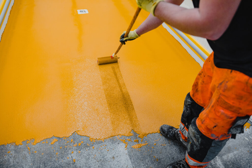 profissional de obra aplicando tinta epoxi em um piso