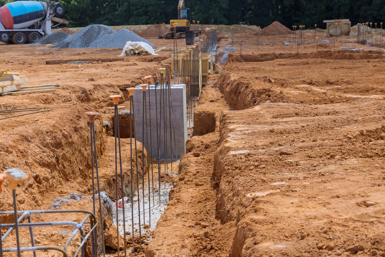 Uma trincheira é cavada para a fundação de concreto em um canteiro de obras e a trincheira é reforçada com barras de aço e fios vergalhões